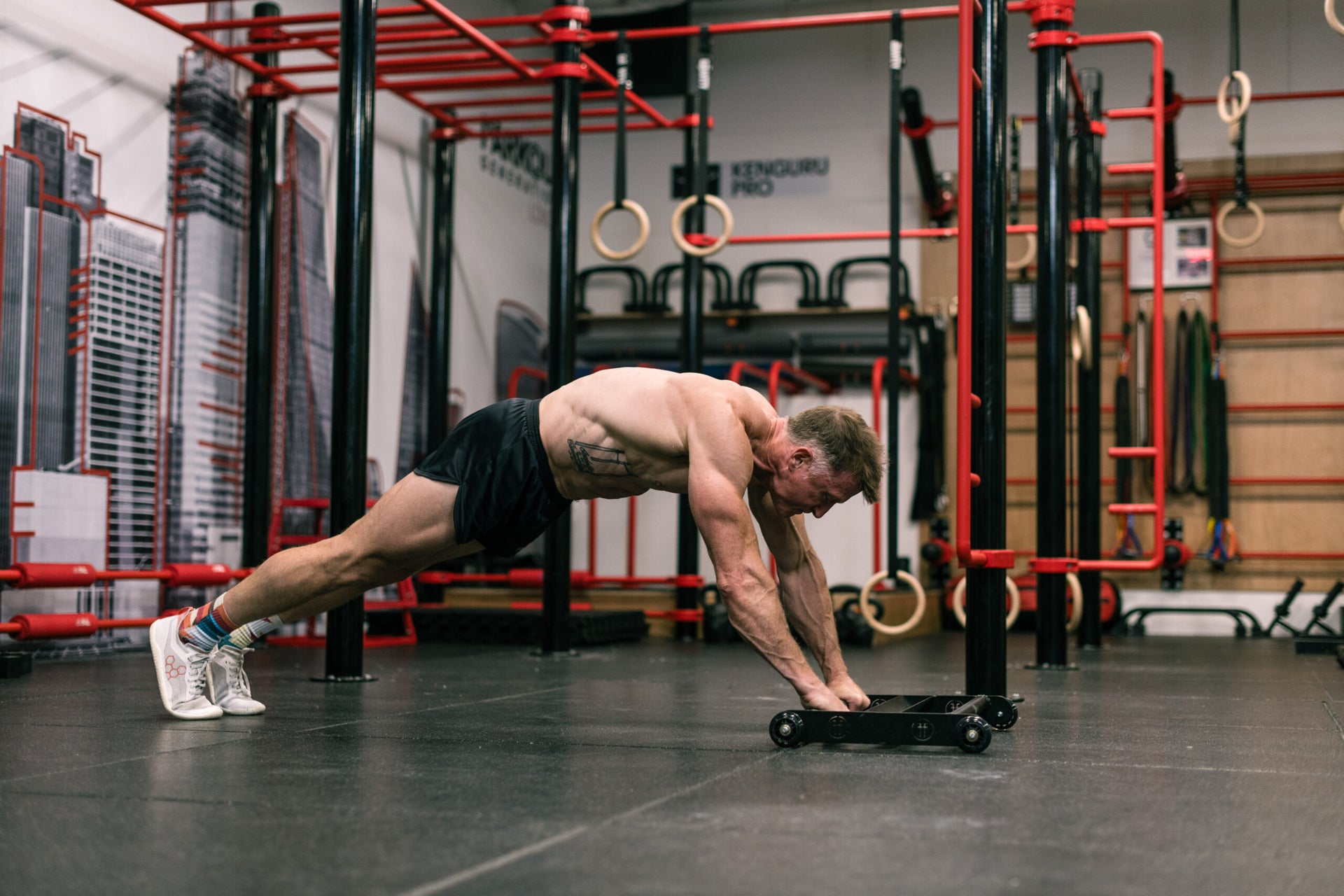 man doing an ab rollout in a gym using a Glute Ham Roller